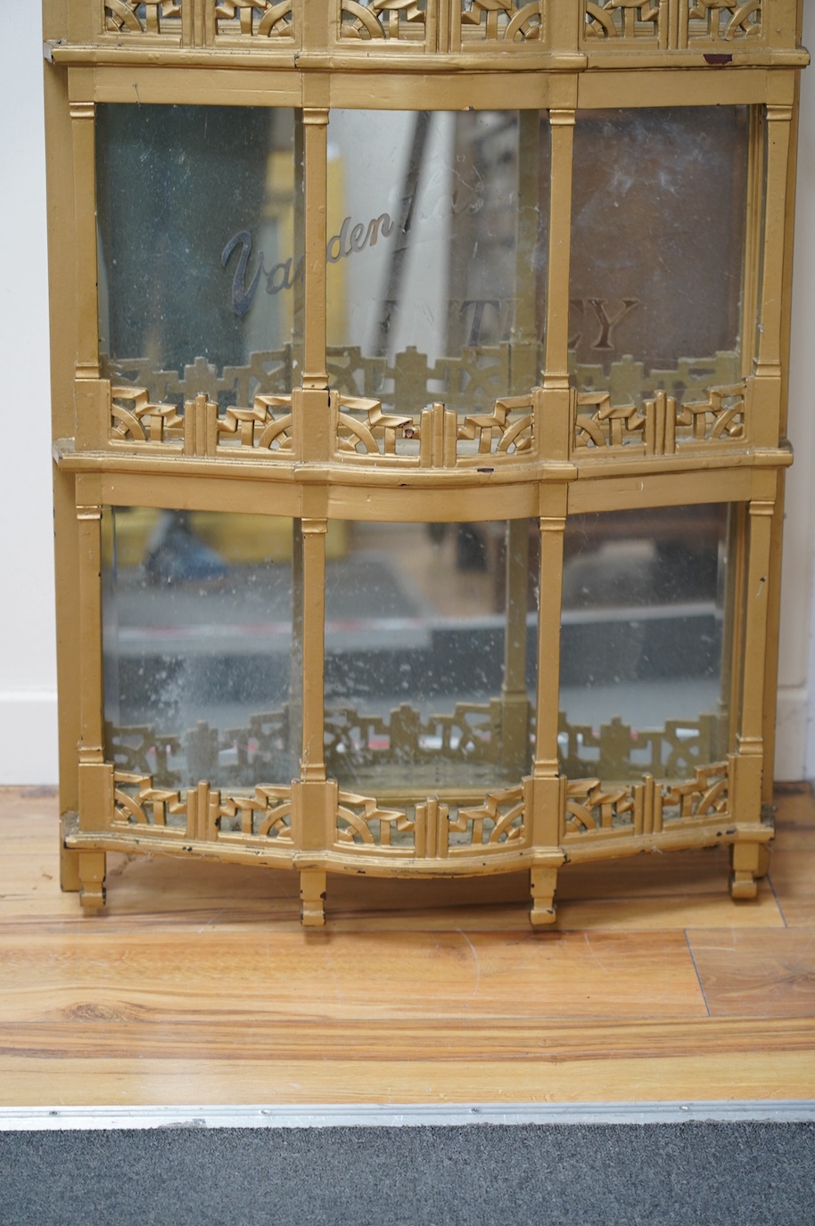 A 1920s gold-painted and mirror backed bow fronted Vanden Plas Bentley mirror-backed automobile showroom display unit, with five galleried shelves in an Art Deco style, each with bevelled mirrors behind and applied lette